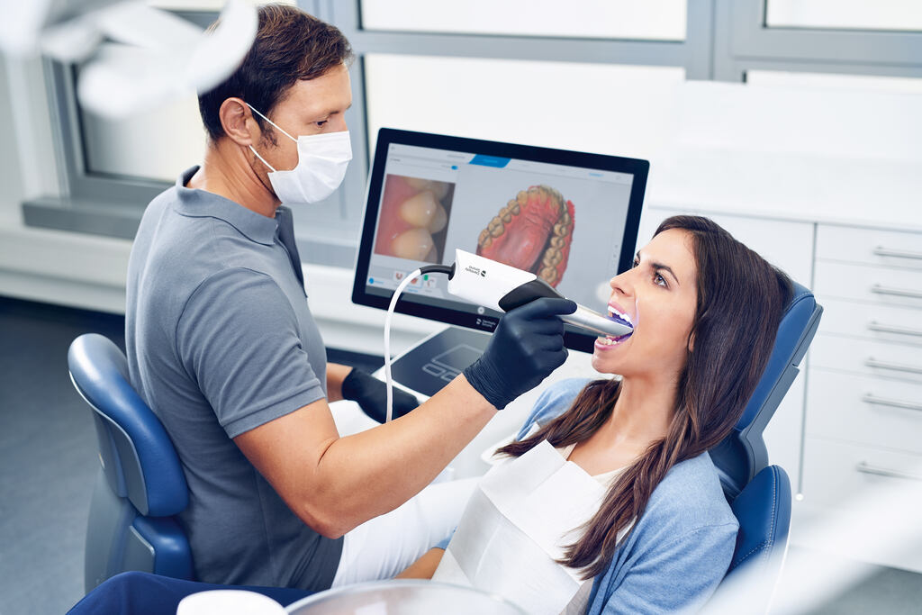 a woman is playing a video game while a man watches  at cosmetic dentistry in Reston, VA